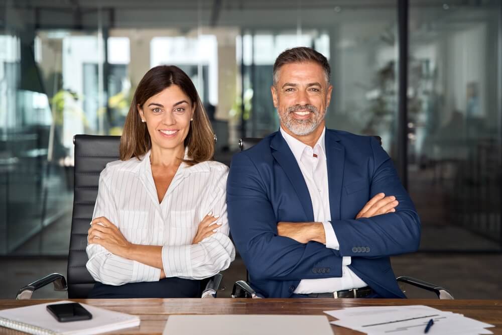 Two insurance professionals sit confidently at a meeting table, representing career growth and how to become a licensed insurance agent.