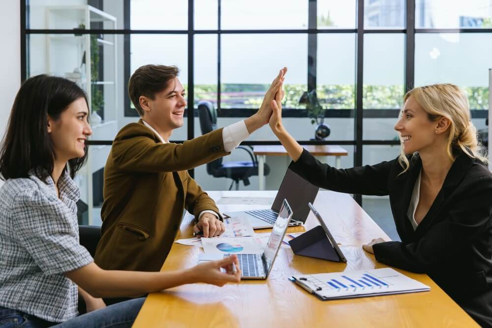 Business professionals celebrate a successful meeting with a high-five, representing collaboration and growth among Hispanic Entrepreneurs.
