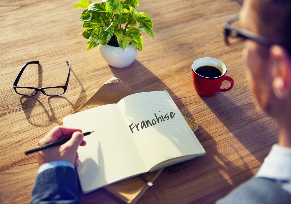 Easy franchise business owner planning a new franchise opportunity at a desk with notebook and coffee
