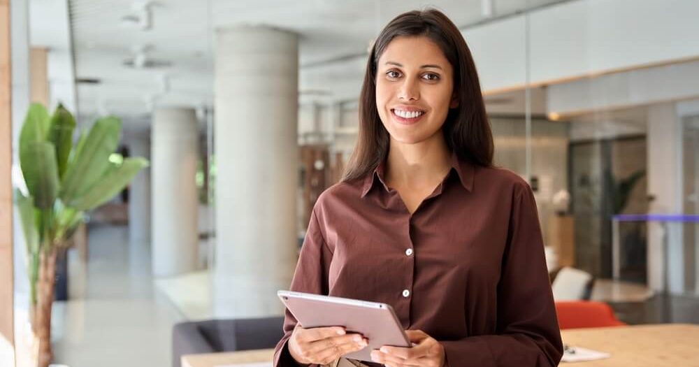 Independent insurance agent holding a tablet in a professional office setting, representing the career opportunities and challenges of becoming an independent insurance agent.