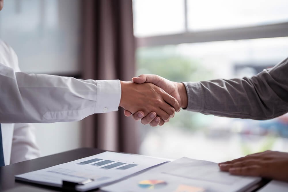 Independent insurance agent shaking hands with a client after discussing coverage options, illustrating the pros and cons of becoming an independent insurance agent.