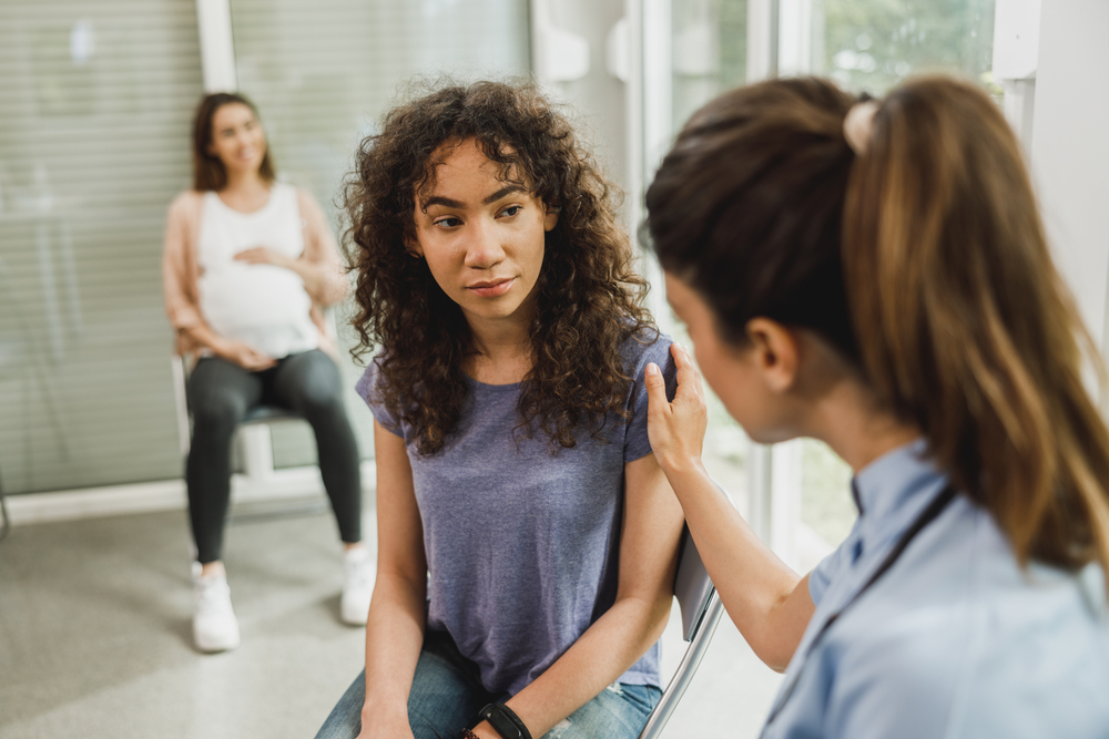 Teenage Hispanic girl talking with female doctor.