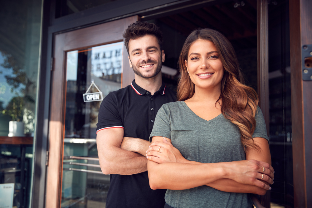 Portrait Of Couple Starting New Business Standing In Doorway 