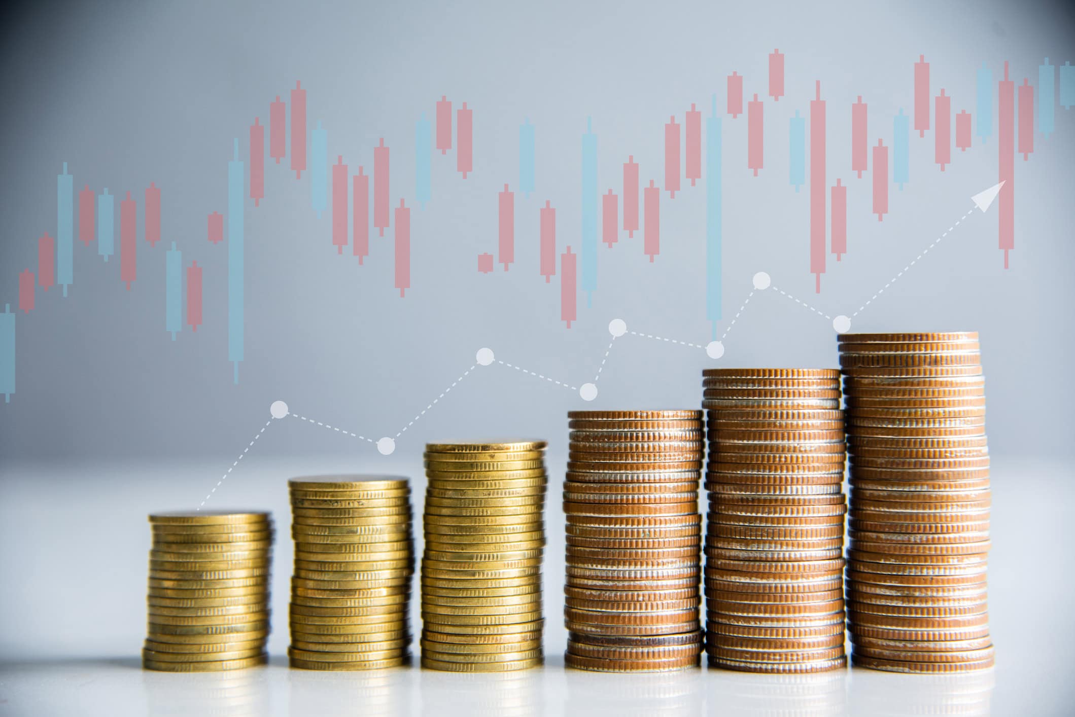 Stacks of coins increasing in height with a rising financial chart, representing insurance agent salary growth and income trends.