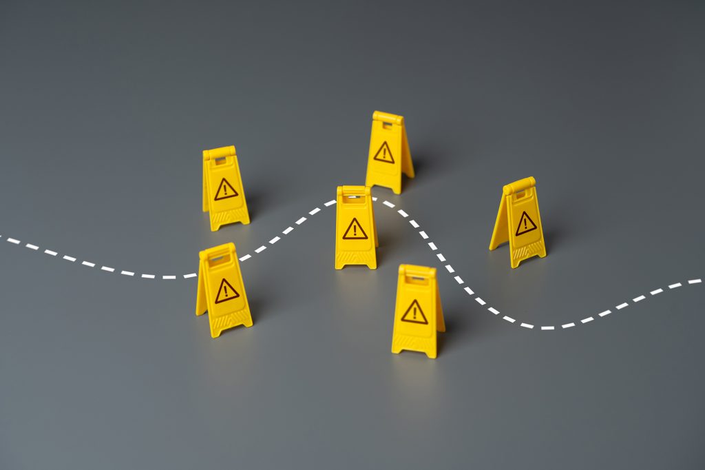 Yellow warning signs along a dashed path symbolizing overcoming transition obstacles