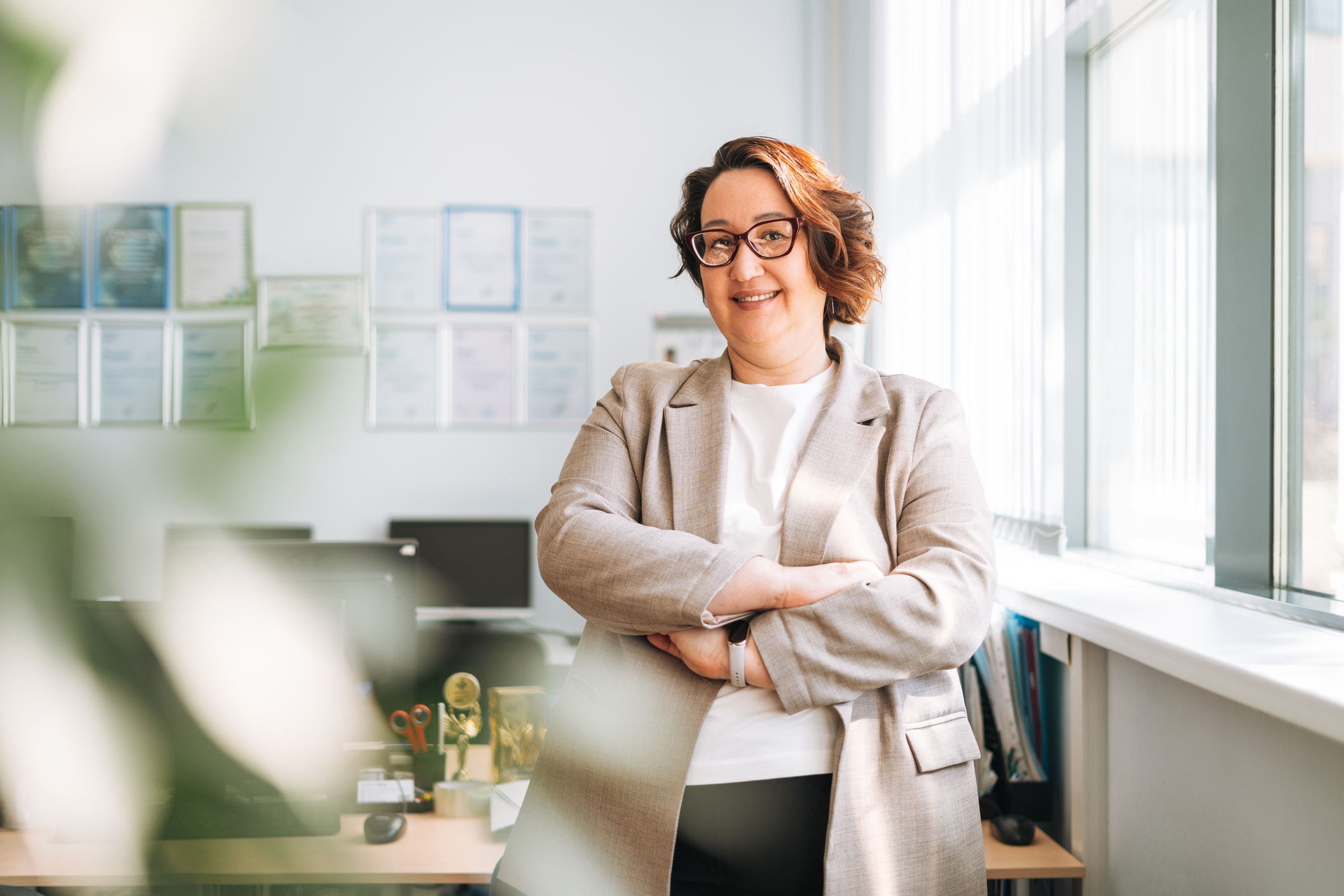Portrait of smiling middle aged brunette woman in glasses and suit in the office.