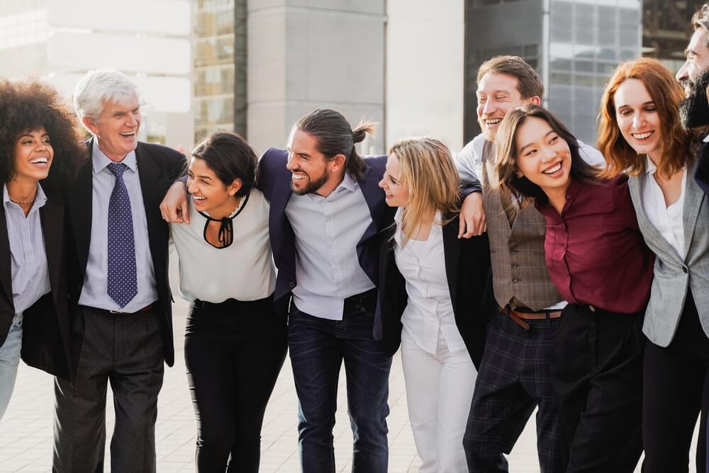 Hispanic entrepreneurs and business professionals stand together outdoors, smiling and celebrating teamwork.