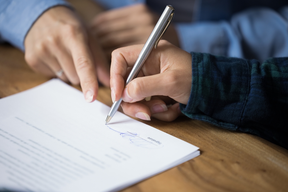 Licensed insurance agent signing an insurance document with a client.