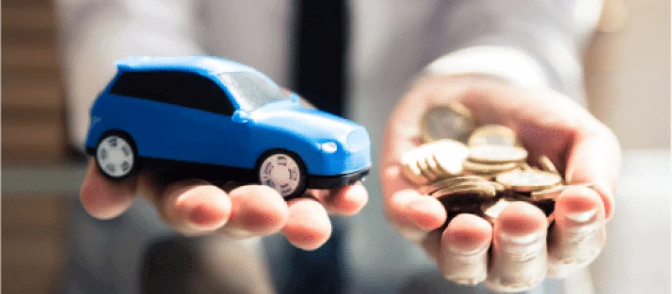 Dos manos de un hombre con un auto miniatura y momendas