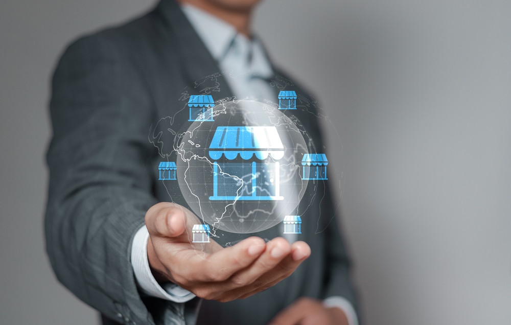 Empresario sostiene íconos de tiendas globales, representando requisitos para abrir un negocio en Estados Unidos.
