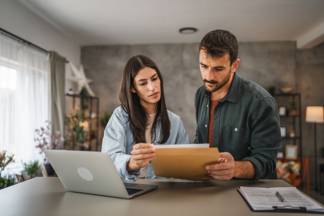 Pareja revisa documentos en casa, analizando requisitos para abrir un negocio en Estados Unidos.