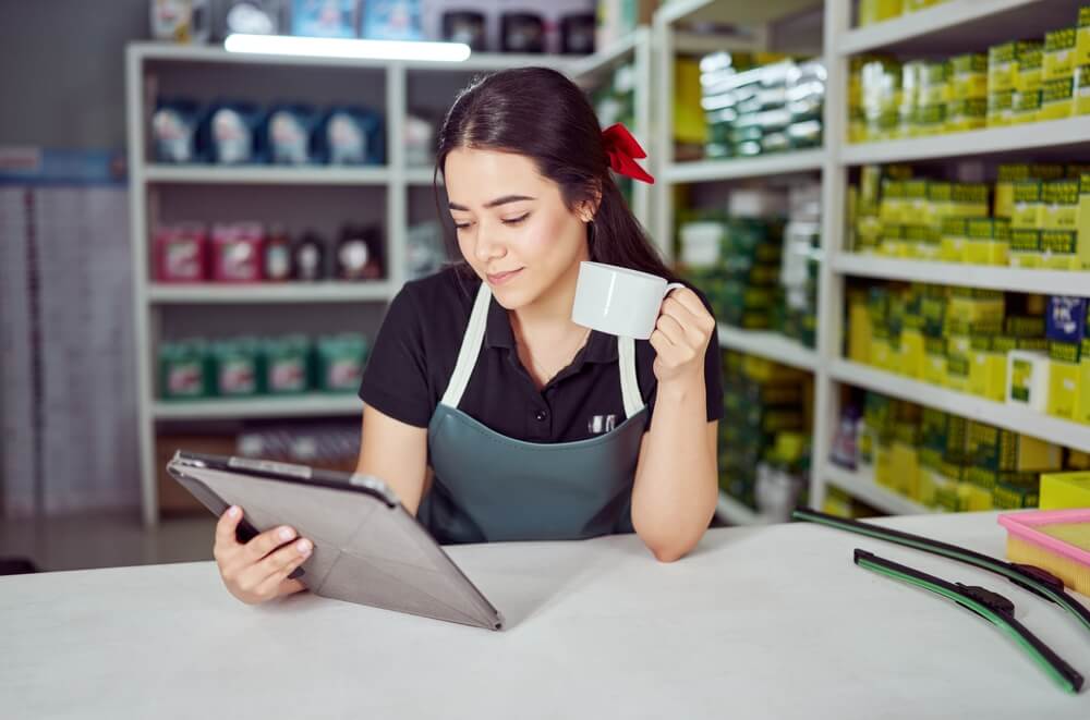 Joven emprendedora revisando una tablet en su tienda, mostrando formas de cómo hacer dinero en USA con pequeños negocios y trabajo independiente.