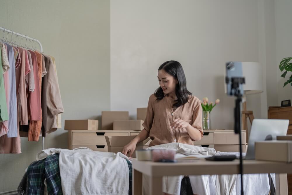 Emprendedora organizando productos para su pequeño negocio de venta de ropa en línea.