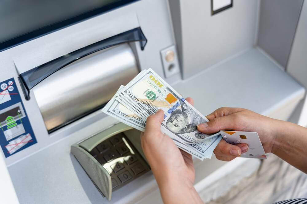 Persona retirando dinero de un cajero automático para operaciones con los mejores bancos de Estados Unidos para franquicias.