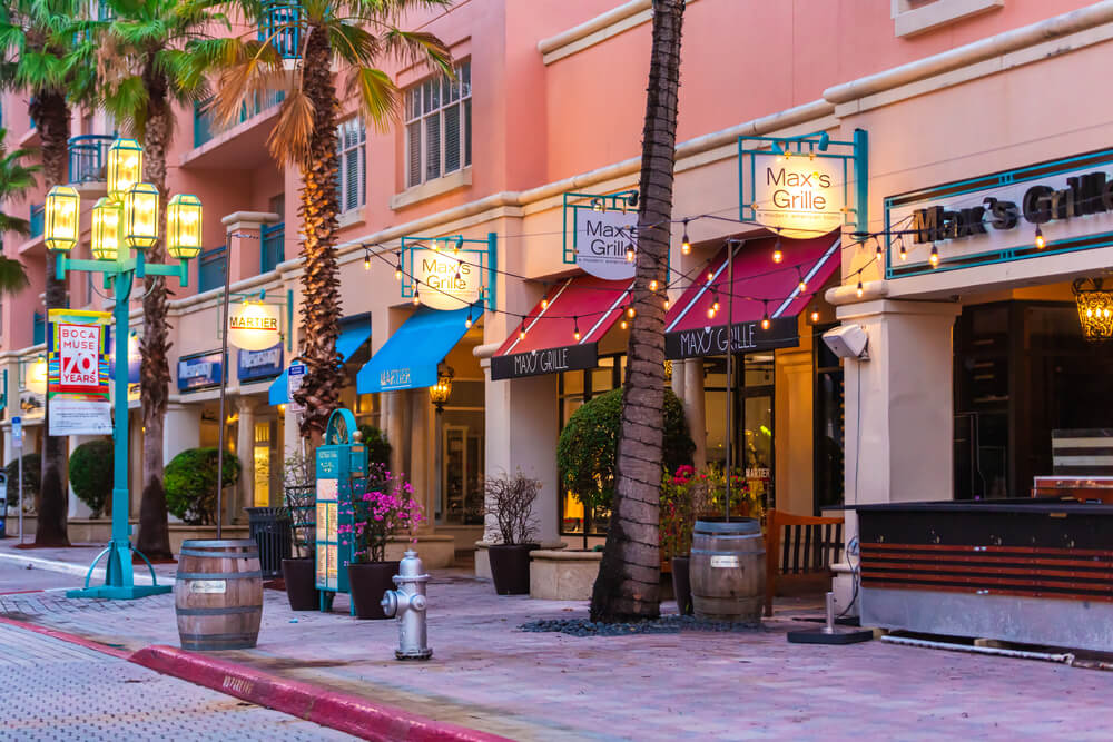 Calle con restaurantes y palmeras en zona comercial, mostrando el ambiente de negocio en Miami.