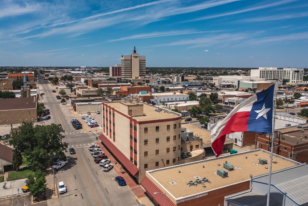 Vista aérea de una ciudad en Texas con la bandera estatal ondeando, representando el entorno empresarial para quienes quieren saber cómo abrir un negocio en Texas.