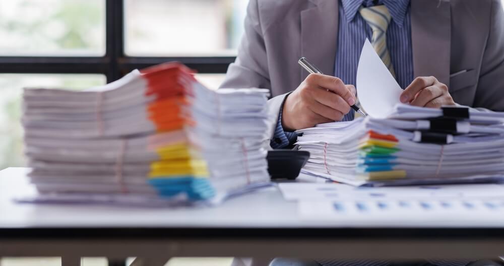 Persona organizando y firmando documentos administrativos en una oficina, representando los trámites y requisitos para abrir una LLC en Estados Unidos.