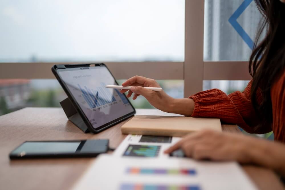 Emprendedora revisando gráficas financieras en una tableta para calcular el capital para abrir una agencia de seguros.