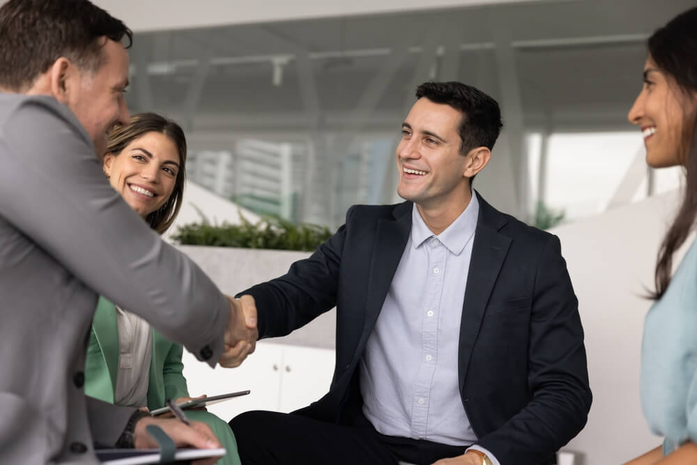 Empresarios estrechando las manos durante una reunión de negocios para planificar el capital para abrir una agencia de seguros.