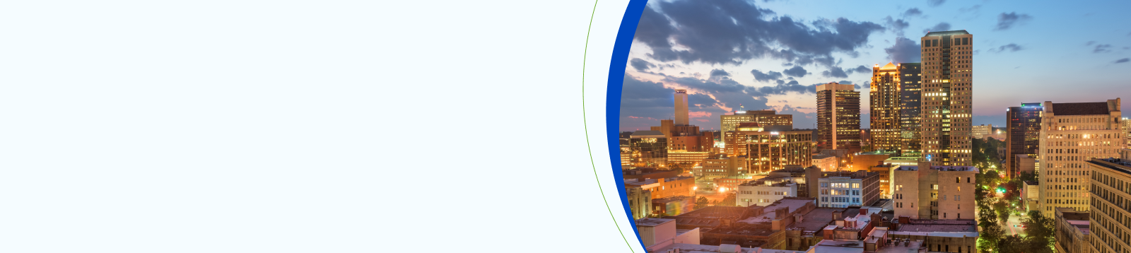 Evening skyline of downtown Birmingham, Alabama, with illuminated office buildings and city lights at sunset.