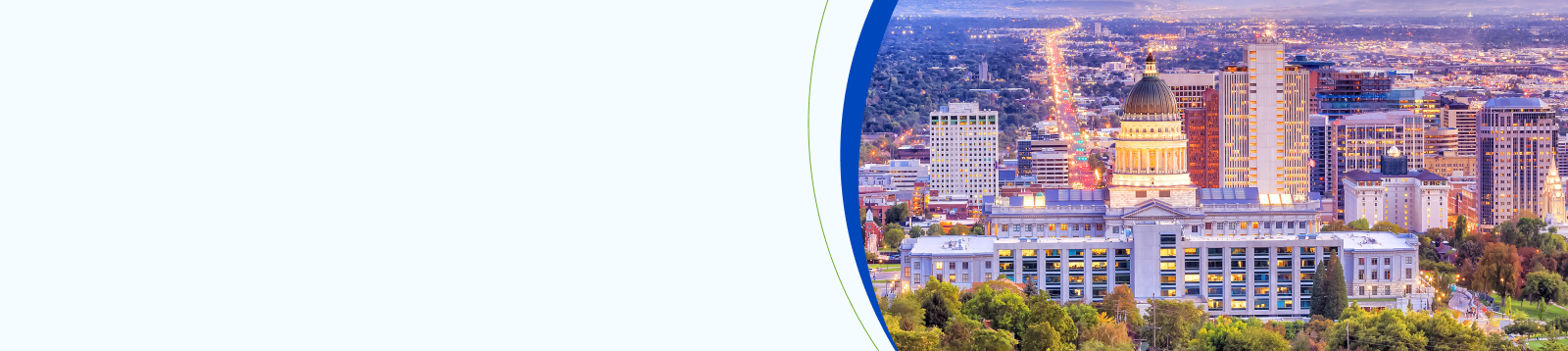 Aerial view of the Utah State Capitol in Salt Lake City at sunset, with the downtown skyline and Wasatch Range in the distance.