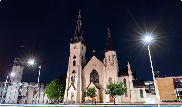 St. Mary's Catholic Church stands in downtown Lincoln, Nebraska, USA. Gothic Revival architecture features twin spires and a modern bell tower illuminated at night.