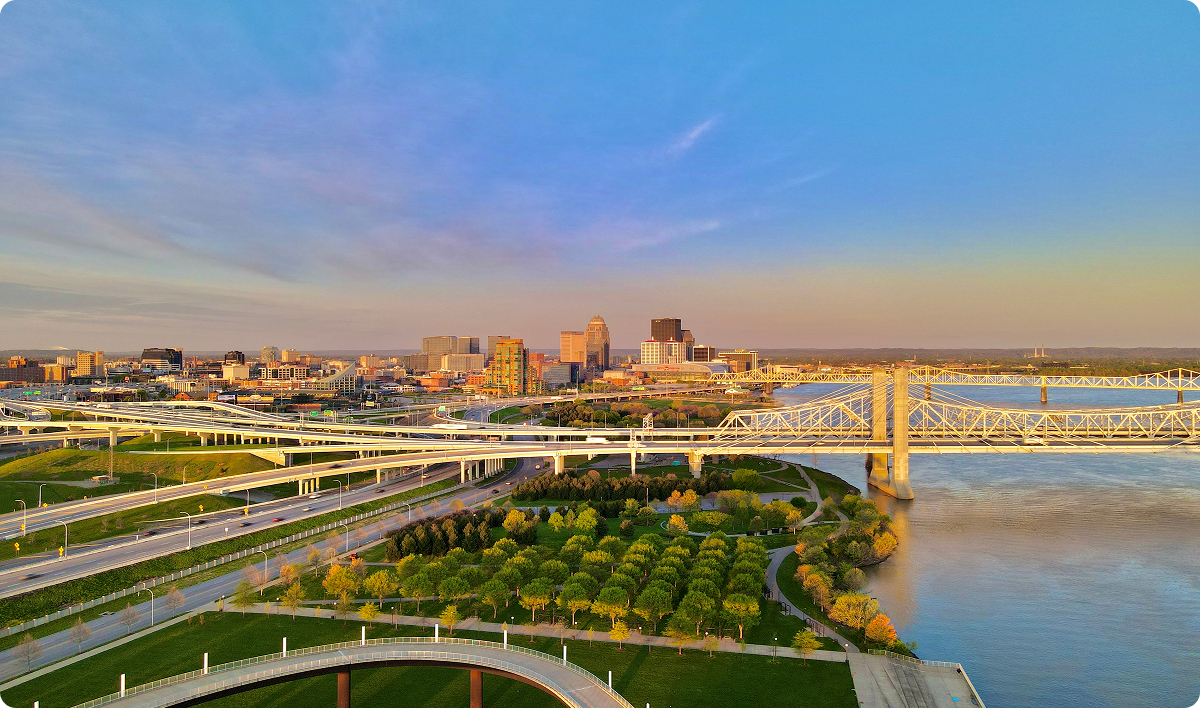 Louisville Kentucky skyline in the morning with bridges crossing a river in foreground.